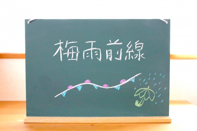 黒板に梅雨前線と書いてある。傘や前線のイラストなど